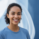 Close-up portrait of a smiling woman with dark hair, conveying happiness and trust against a soft, blurred background.